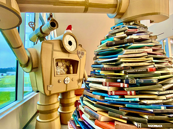 Jason Jones' robot at the library with the Christmas tree made out of books.